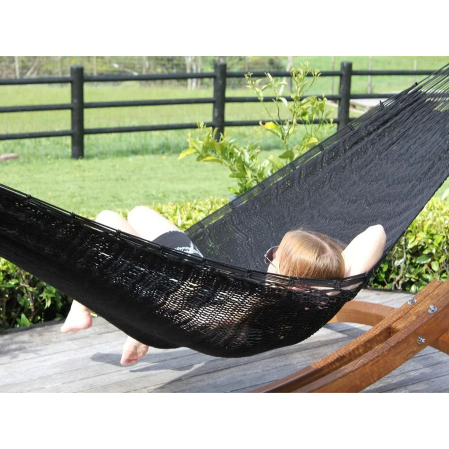 Black polyester woven hammock hung on frame on deck overlooking farmland