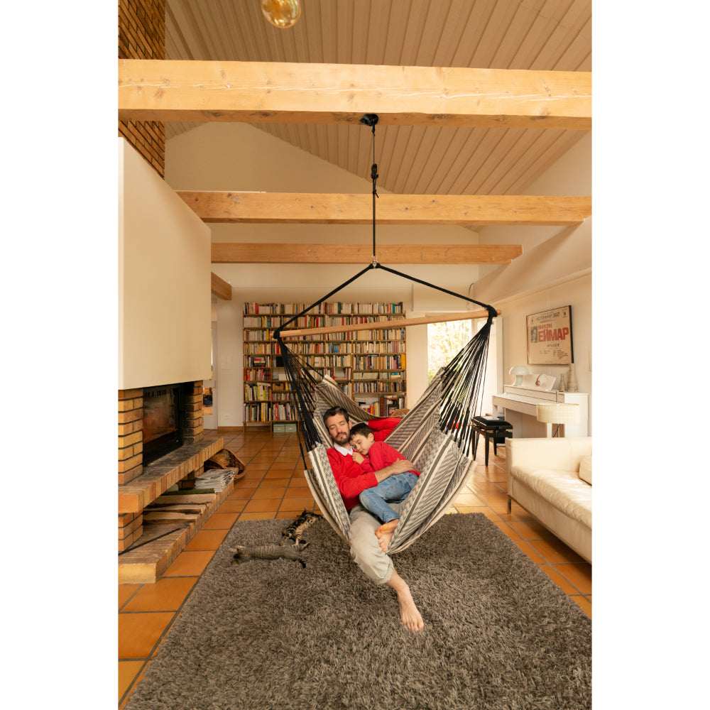man and child relax in hammock chair indoors