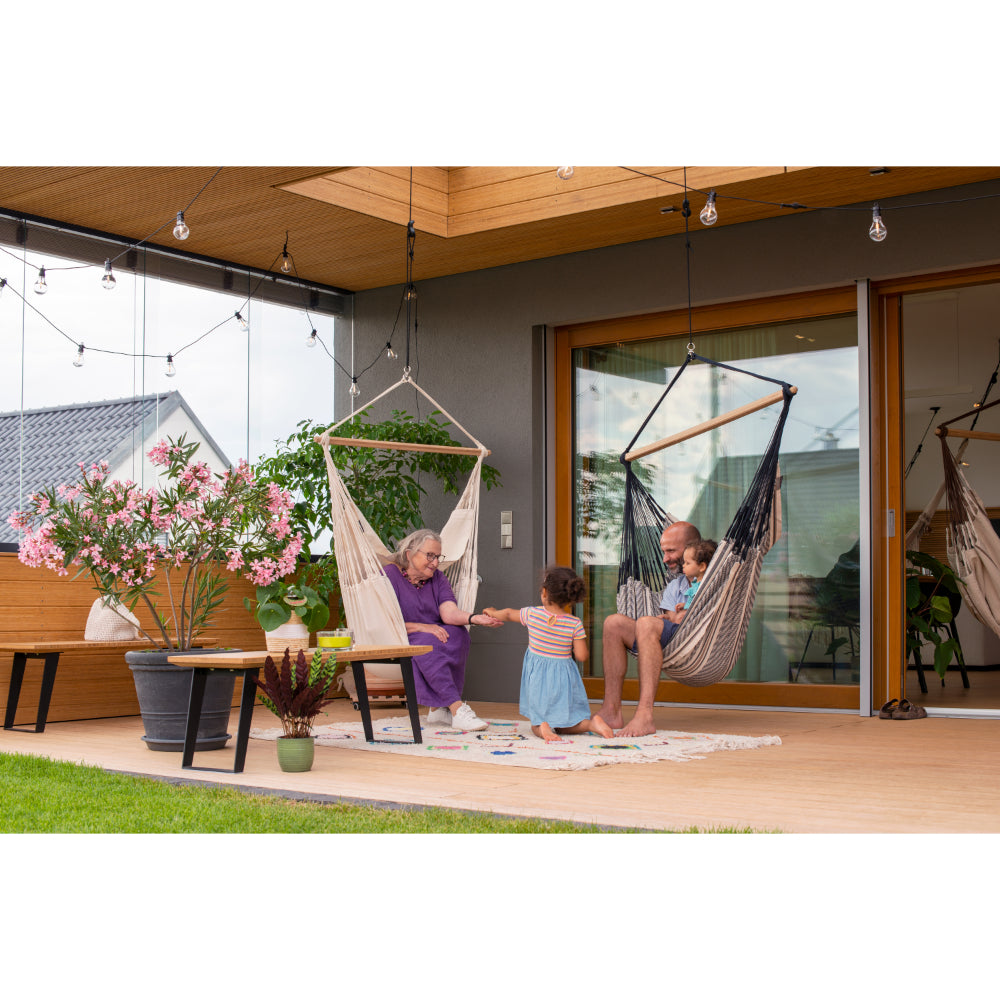 elderly woman and man relax in hammock chairs with children in outdoor porch area