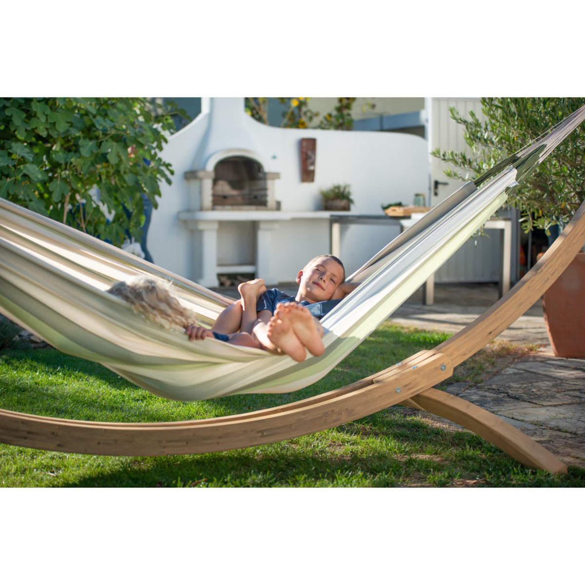 Children relaxing in double hammock in garden