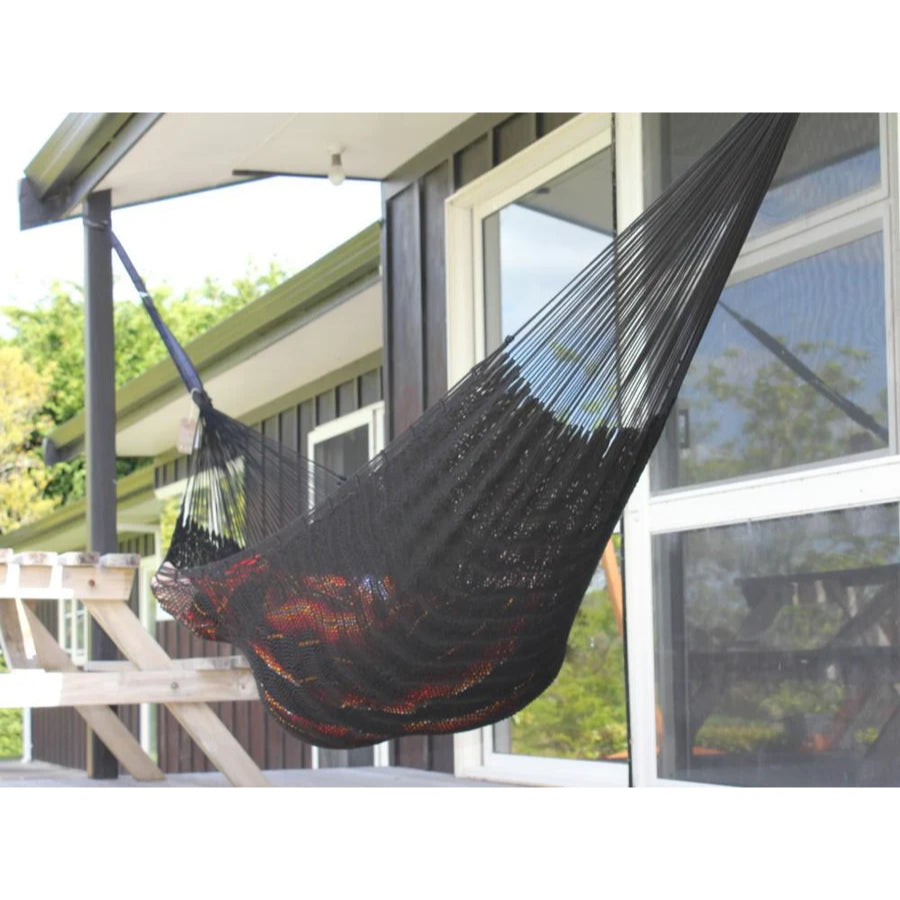 Black hammock hanging on a deck outside a home