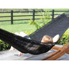 Black polyester woven hammock hung on frame on deck overlooking farmland