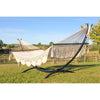 White cotton Mexican spreader bar hammock on metal stand on grass lawn